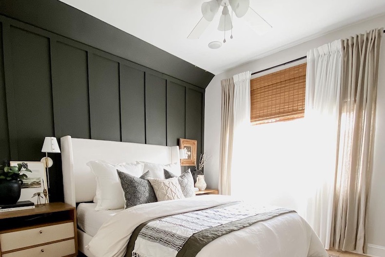 A black accent wall in a well lit bedroom.